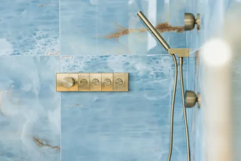 Shower with brass fixtures and blue stone tile